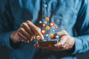 man holding phone looking at instagram and facebook emojis