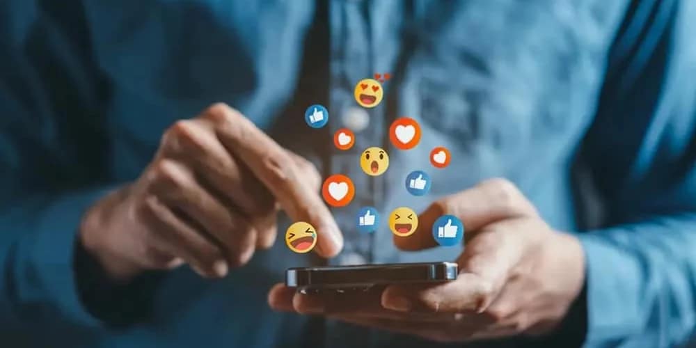 man holding phone looking at instagram and facebook emojis